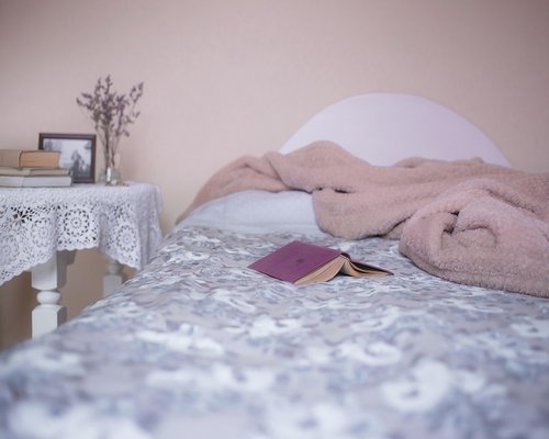Dimly lit bedroom side table next to a tidy bed showing digital disconnection