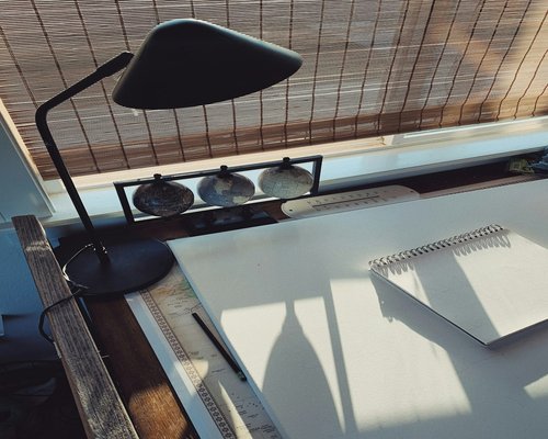 Organized workspace table positioned nicely perpendicular to a bright natural light window
